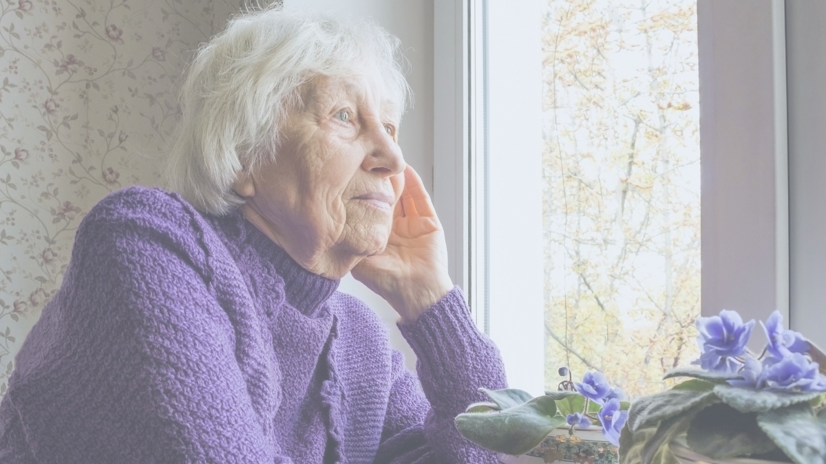 Elderly woman looking out window.