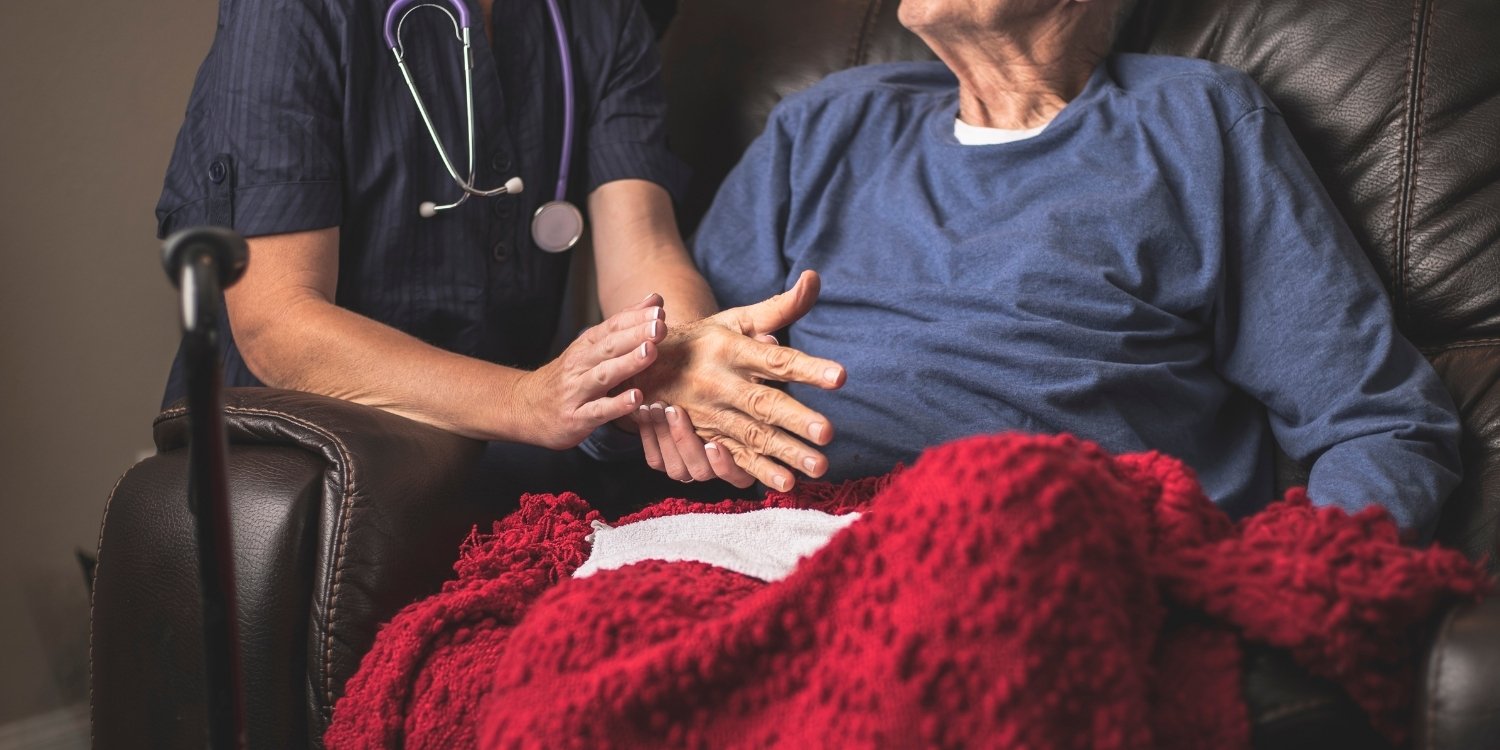 Clinician holding an elderly patient's hands.