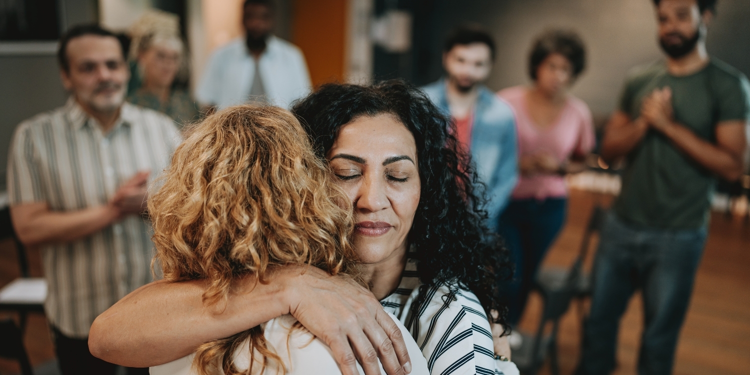 Two people embracing at a grief support group