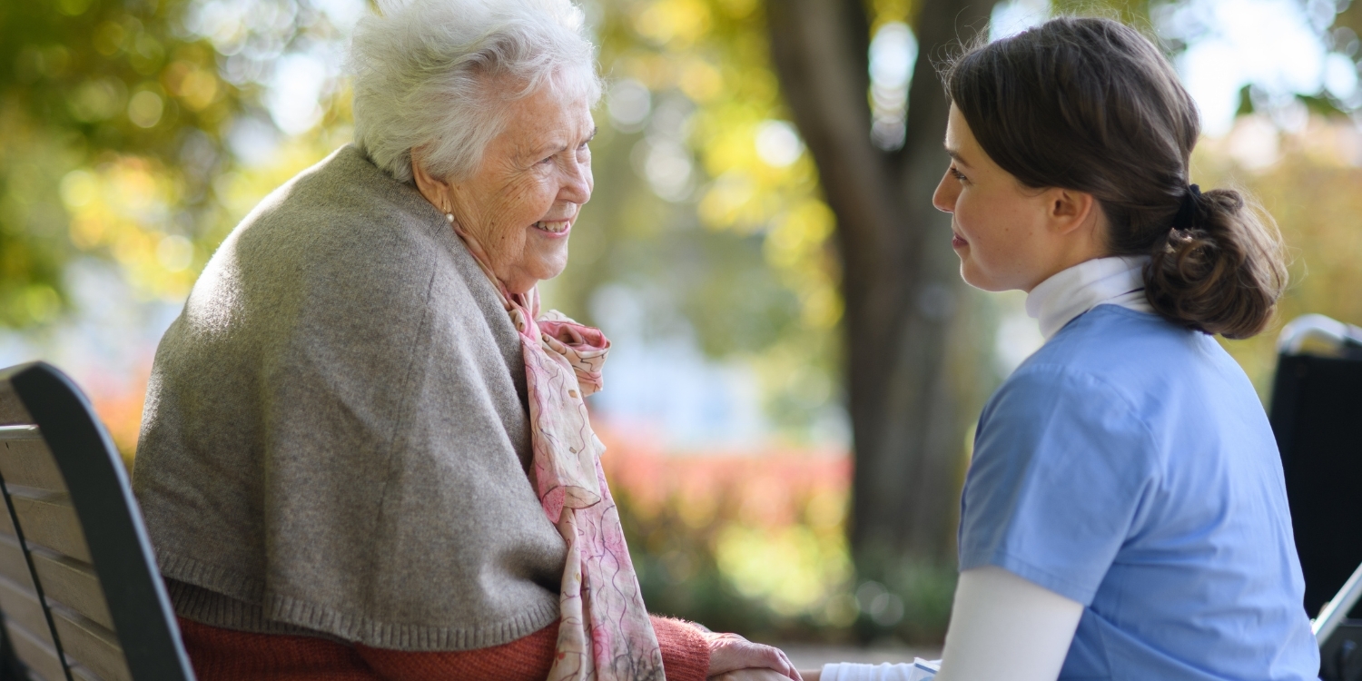 Senior woman sitting at a park with a hospice nurse