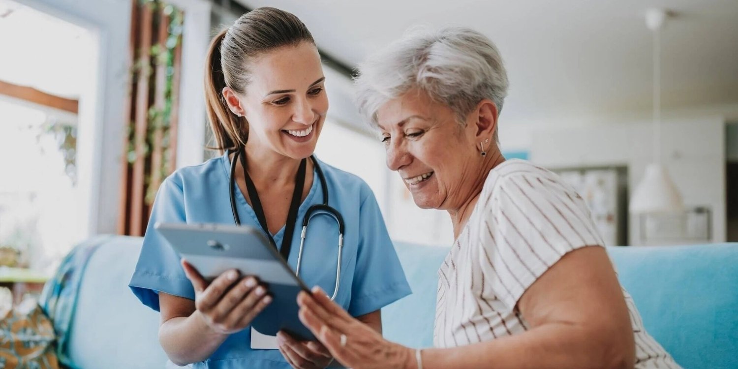 Smiling clinician showing elderly patient a tablet.