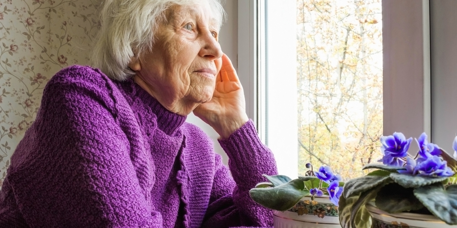 Elderly woman looking out window.